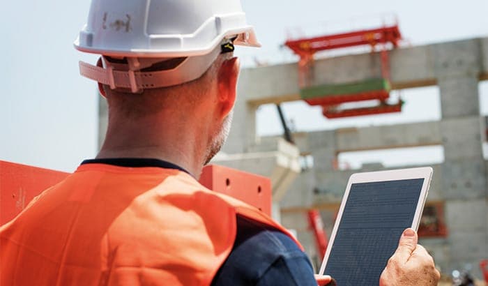 Ingenieur mit Helm dokumentiert ein Bauwerk mit dem Tablet