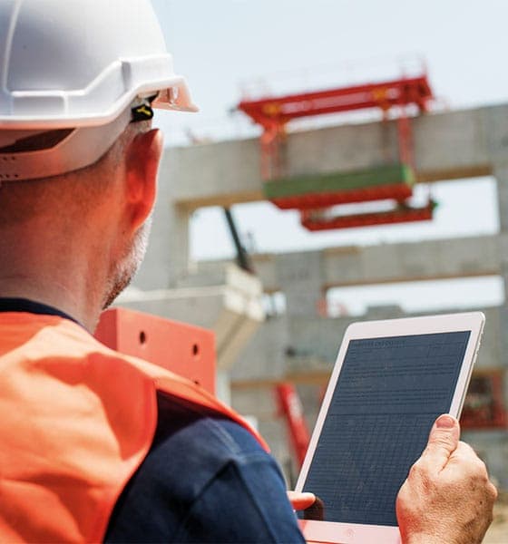 Bauleiter mit Helm und Tablet auf der Baustelle